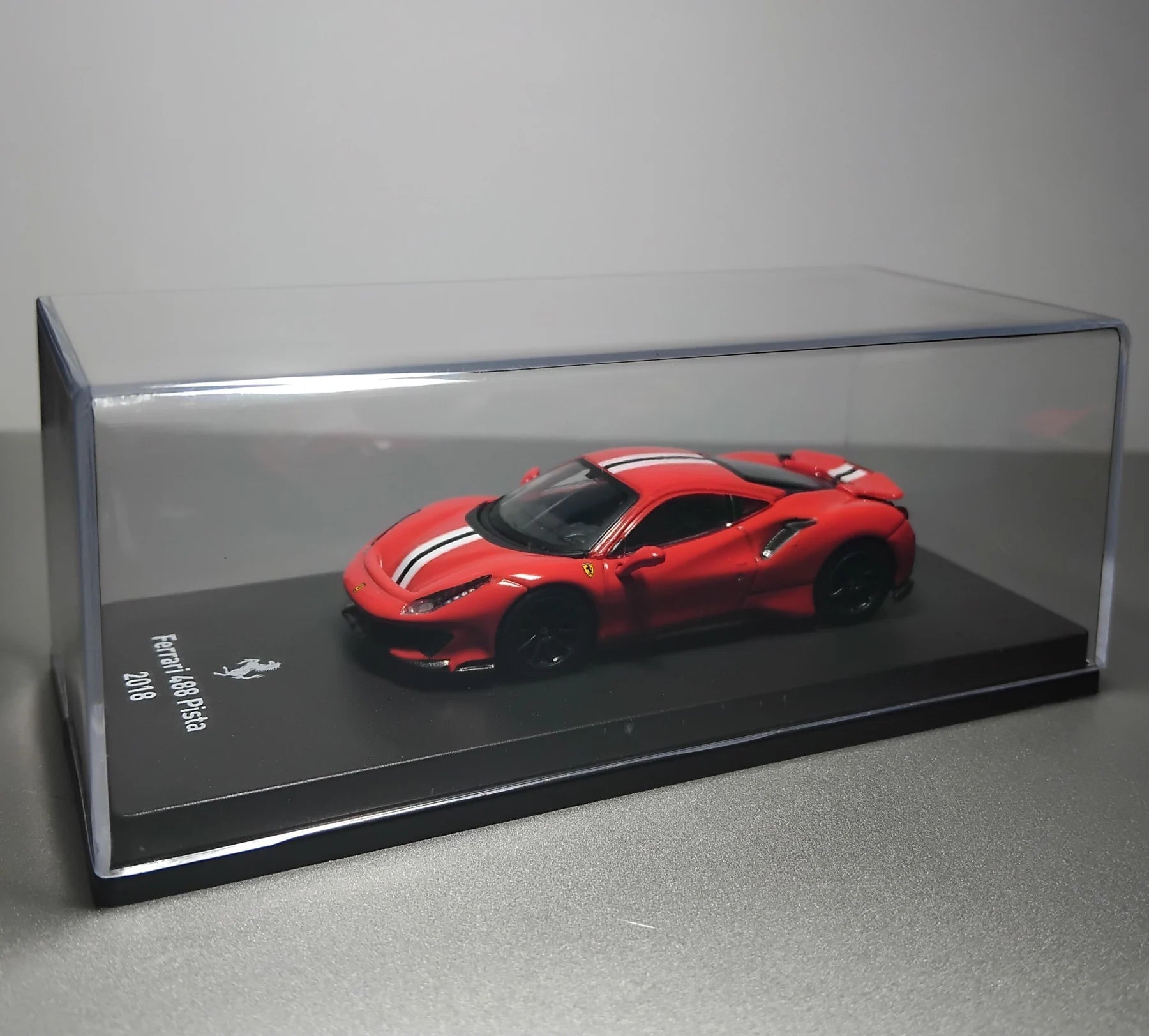 Rote Ferrari-Miniatur in einer transparenten Vitrine auf einem Sockel
